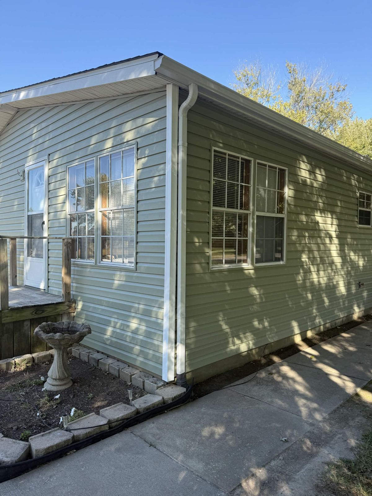 Corner detail of completed vinyl siding showing the lap profile, white corner trim and downspout